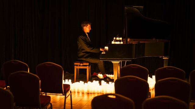 Pianista widziany zza rzędów czerwonych krzeseł